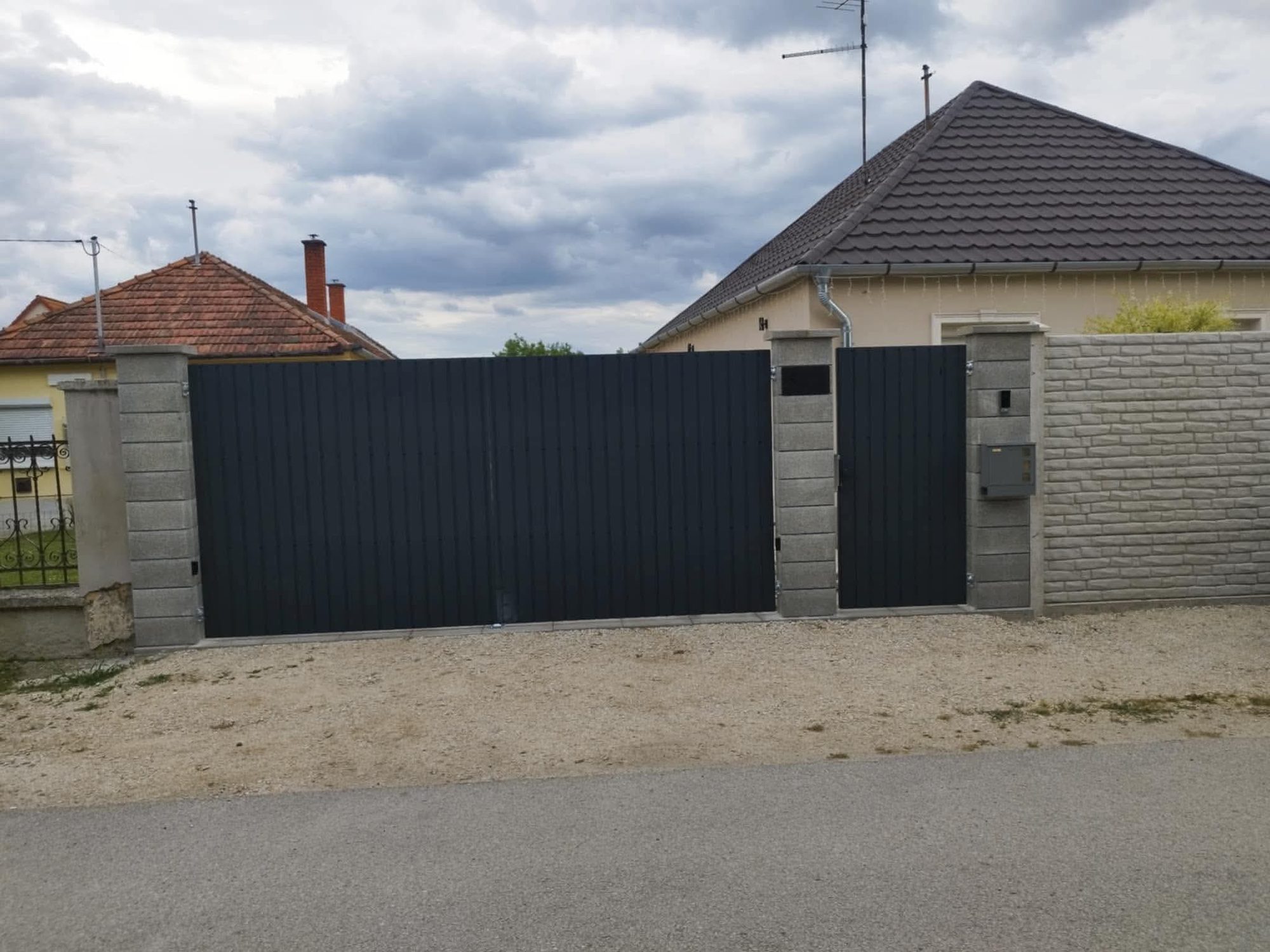 Anthracit színű, porszórt acél bejárati kapu egy családi ház előtt